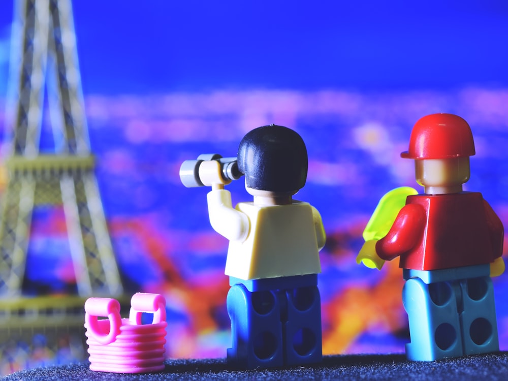 a couple of legos are standing in front of the eiffel tower