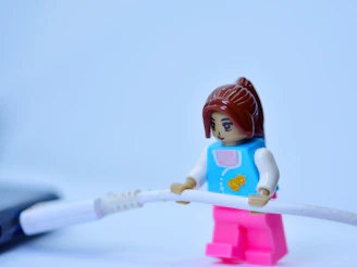 Trish from Hogan's Great Sandwiches as lego girl holding a USB cord on a white surface