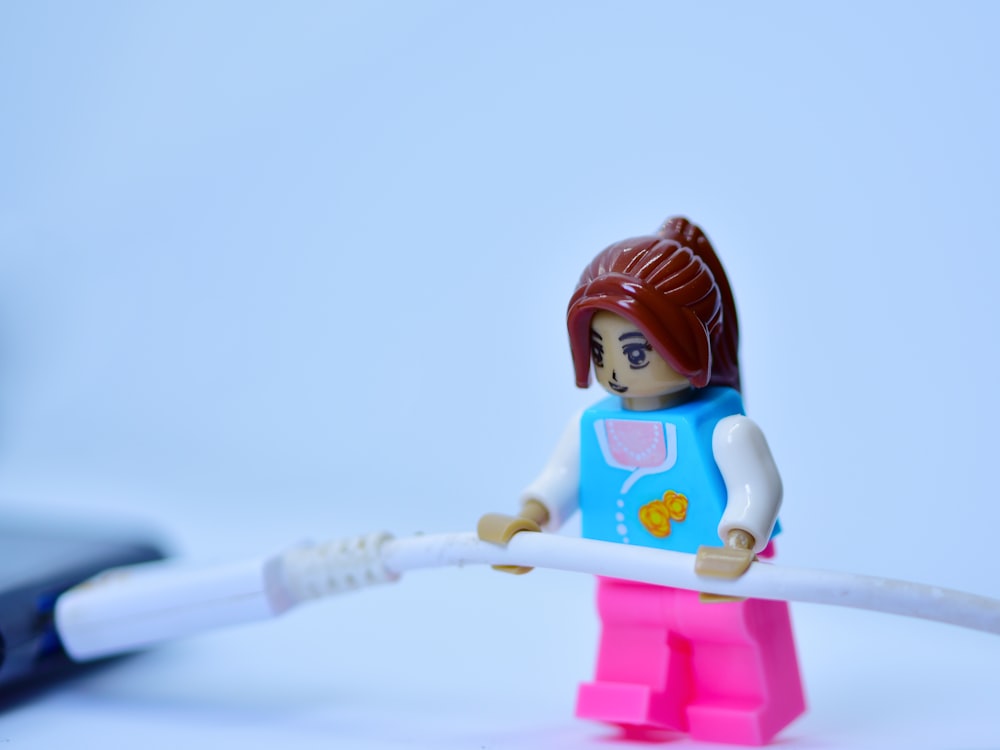 a lego girl holding a toothbrush on a white surface