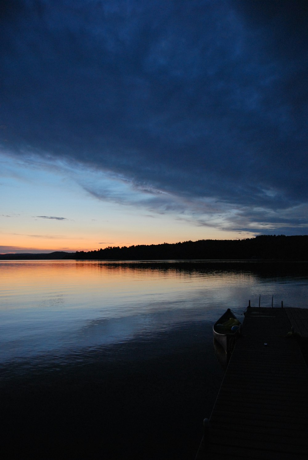 a boat sitting on top of a lake under a cloudy sky