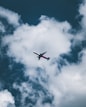 an airplane flying through a cloudy blue sky