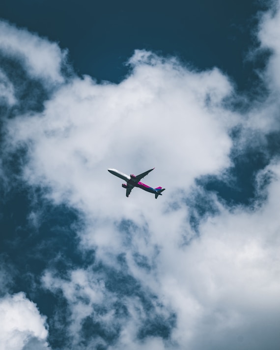 an airplane flying through a cloudy blue sky