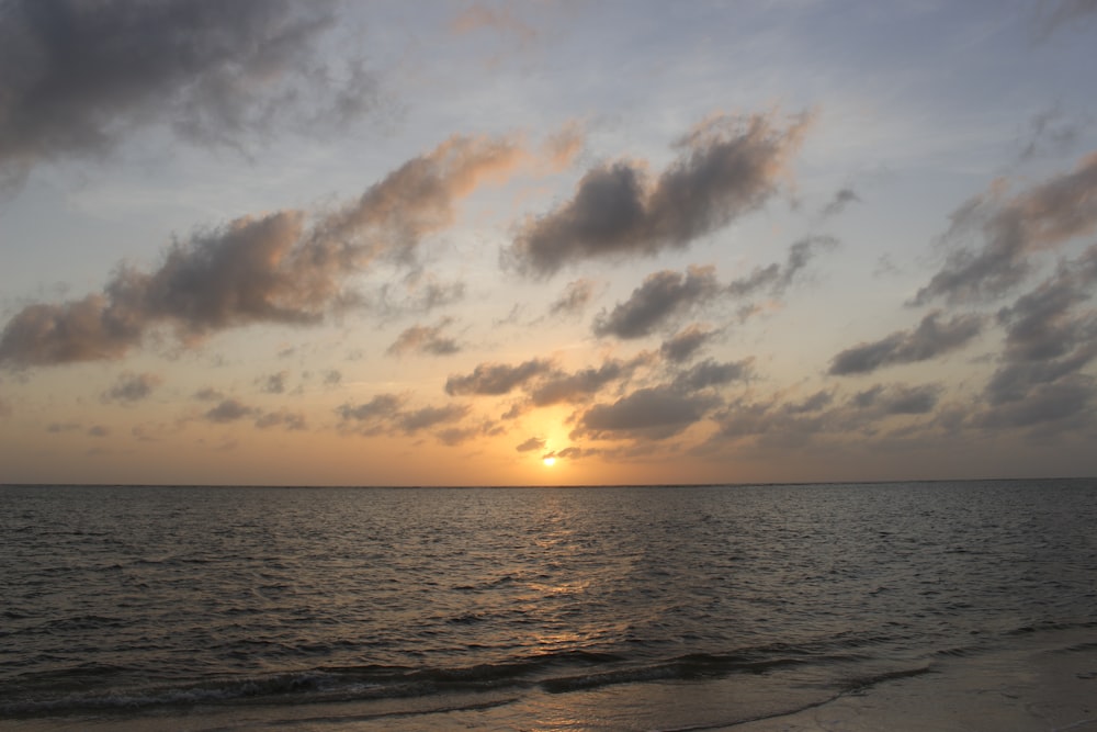 Il sole sta tramontando sull'oceano in una giornata nuvolosa