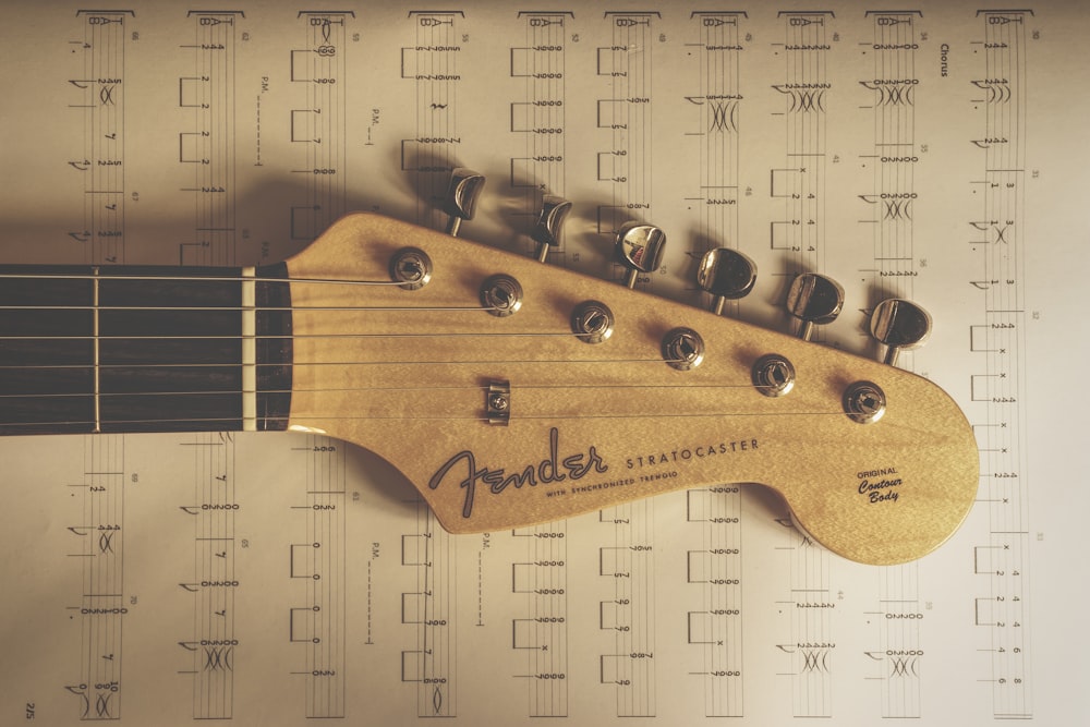 a close up of a guitar neck on a sheet of music