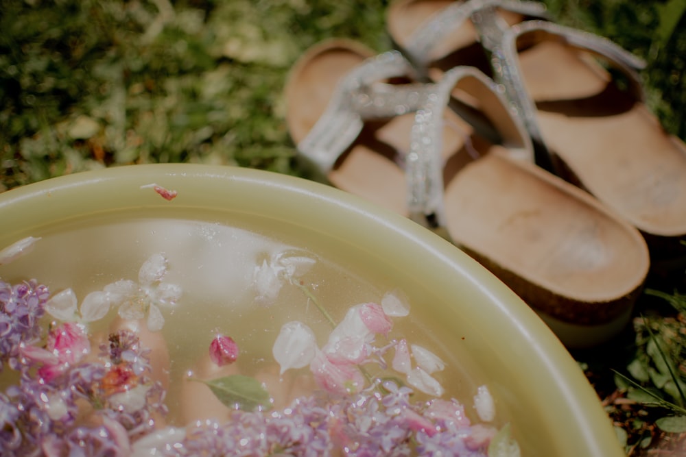a pair of sandals sitting next to a bowl of flowers