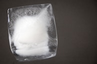 A close-up of dry ice sublimating into gas in a clear container.