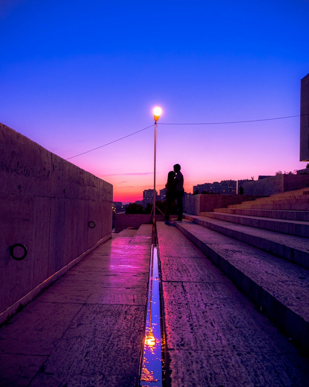 Uomo in giacca nera che cammina sulla strada di cemento grigio durante la notte