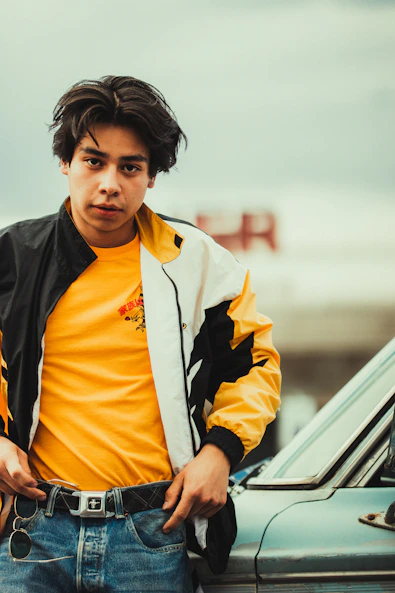 a young man standing next to a parked car