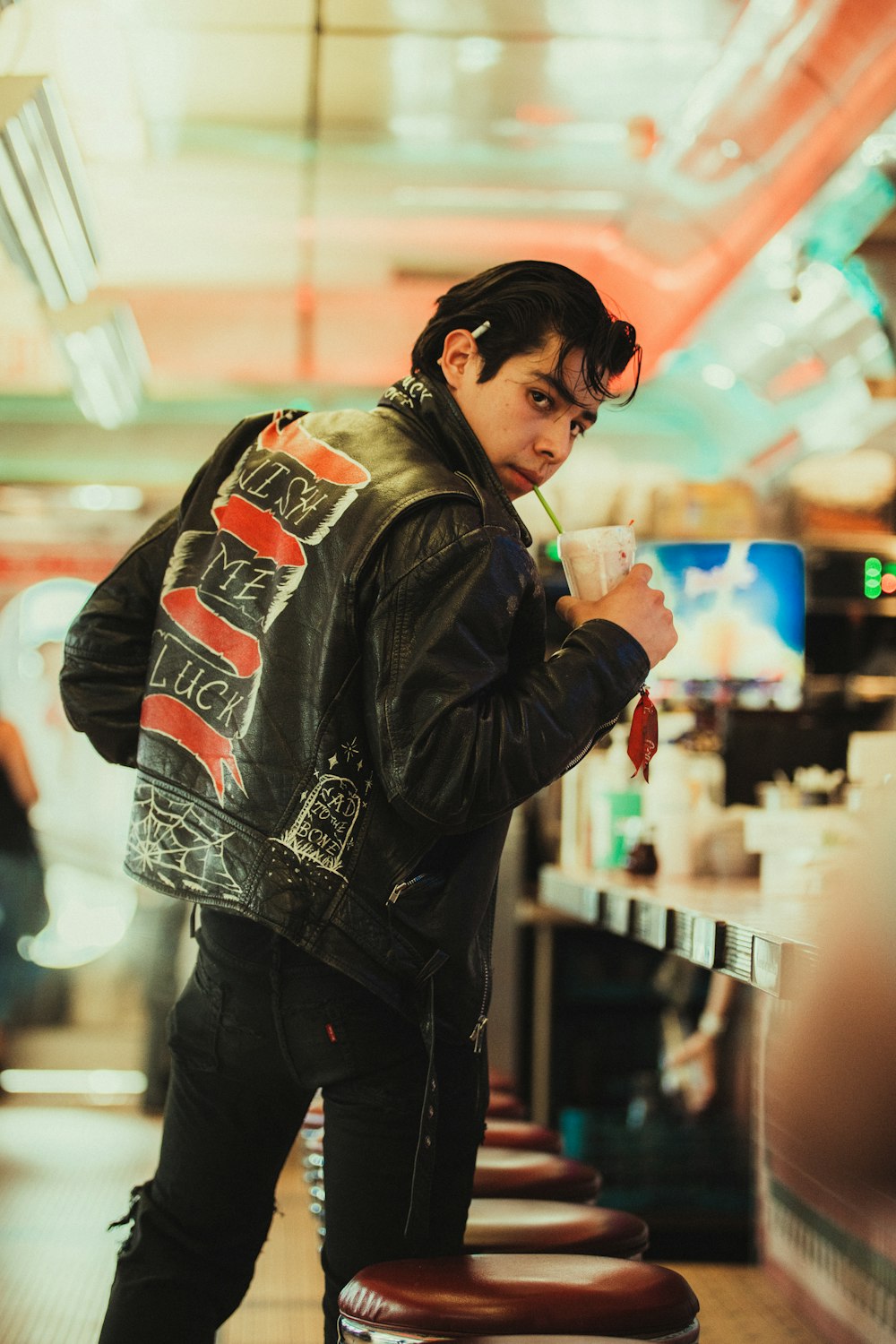 a man in a leather jacket drinking a drink