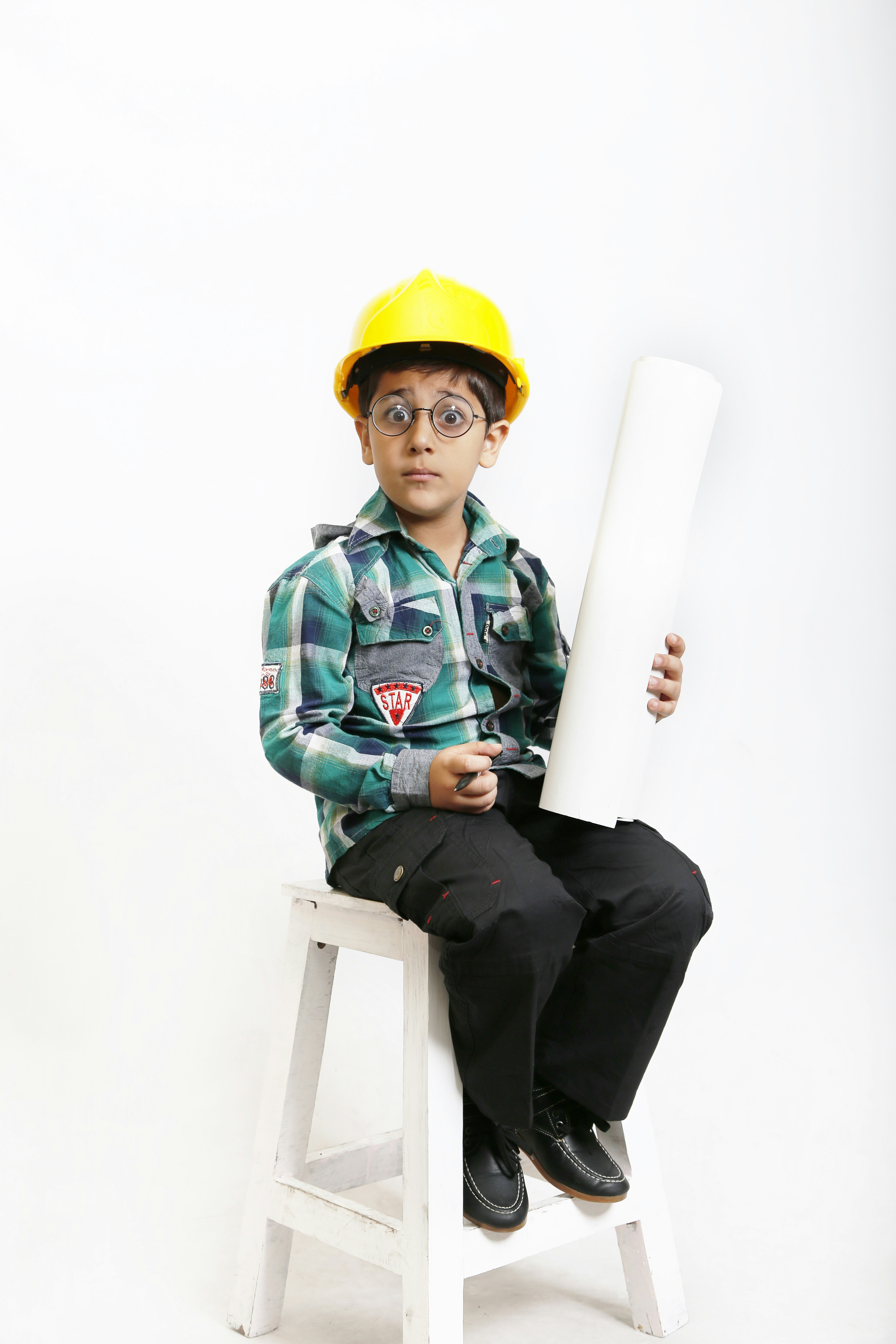 a young boy sitting on a stool holding a piece of paper