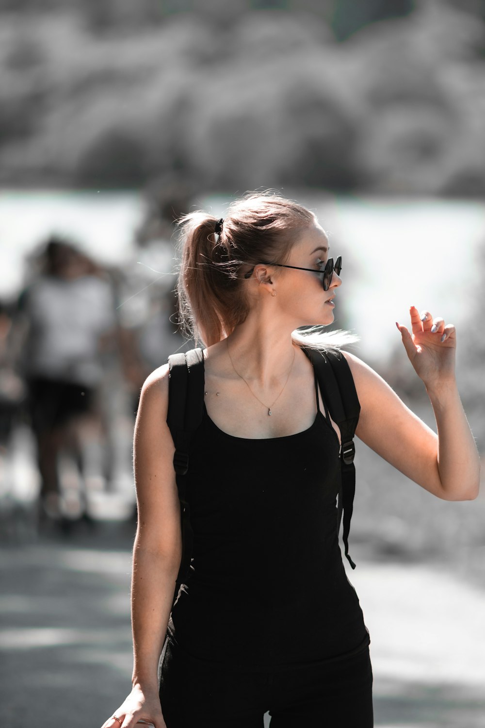 Une femme vêtue d’un débardeur noir et de lunettes de soleil