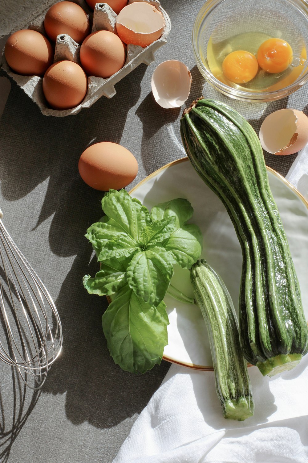 a plate with cucumbers, eggs, and a whisk on it