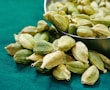 a metal bowl filled with green cardamoa seeds