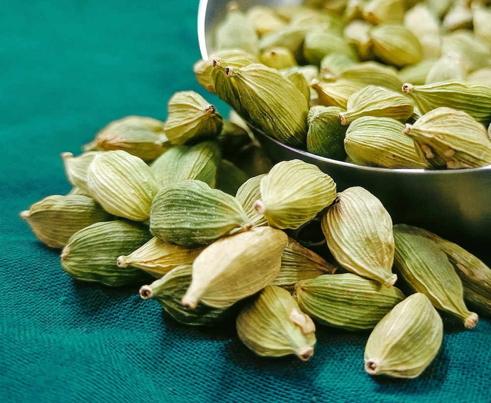 a metal bowl filled with green cardamoa seeds
