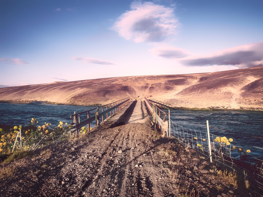 brown wooden fence on brown sand near body of water during daytime