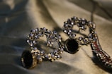 Intricately designed earrings adorned with small pearls and crystals are arranged artistically on a silky fabric backdrop, reflecting light and showcasing their elaborate craftsmanship.