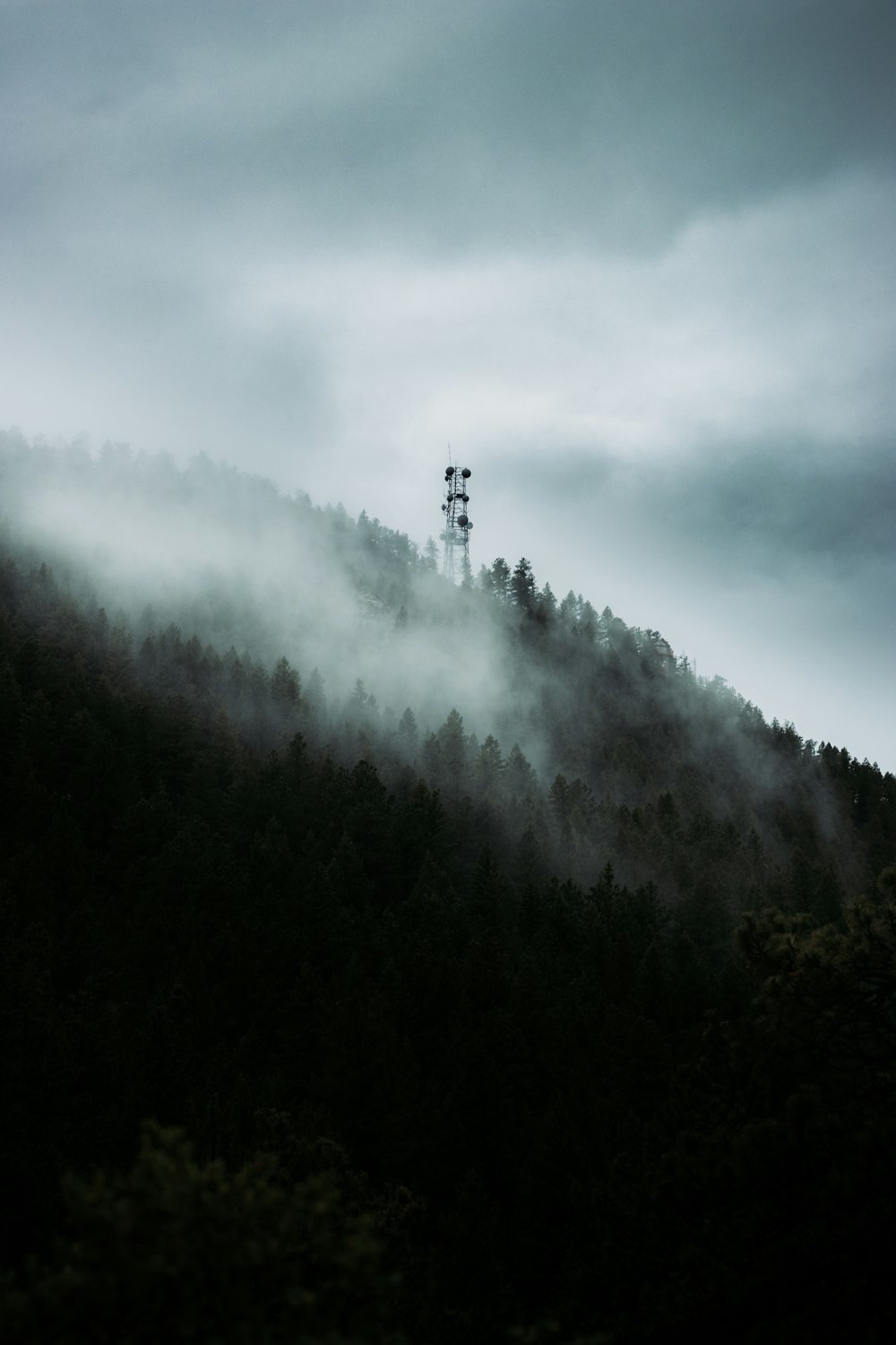 a foggy mountain with a tower in the distance