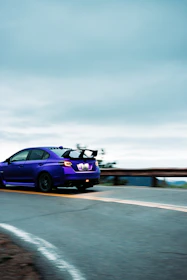 A dynamic photo of a car influencer filming a performance car on a scenic road.