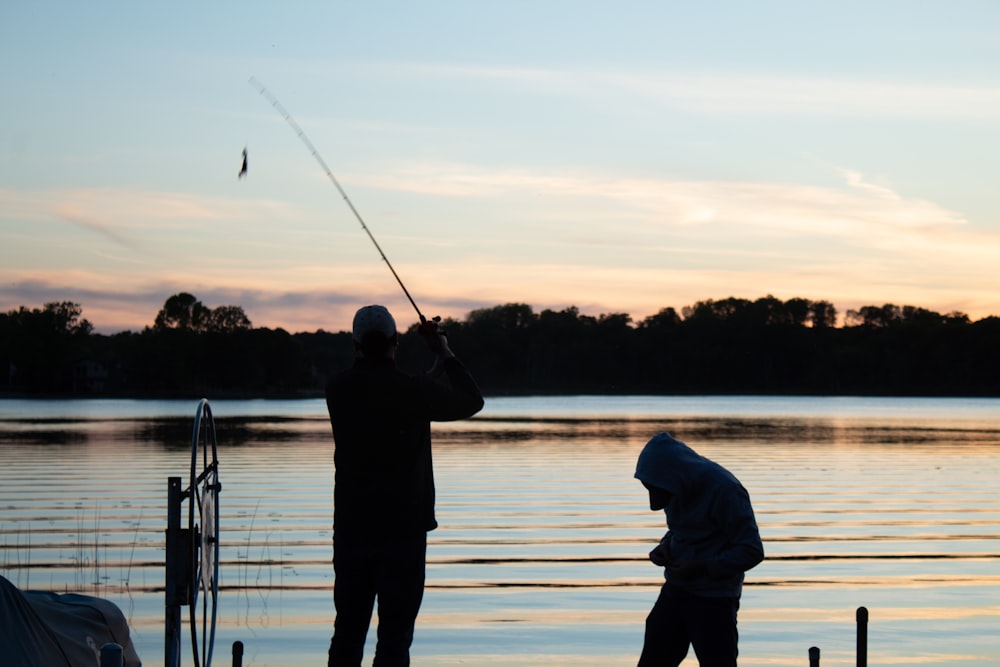 dois homens pescando em um lago ao pôr do sol