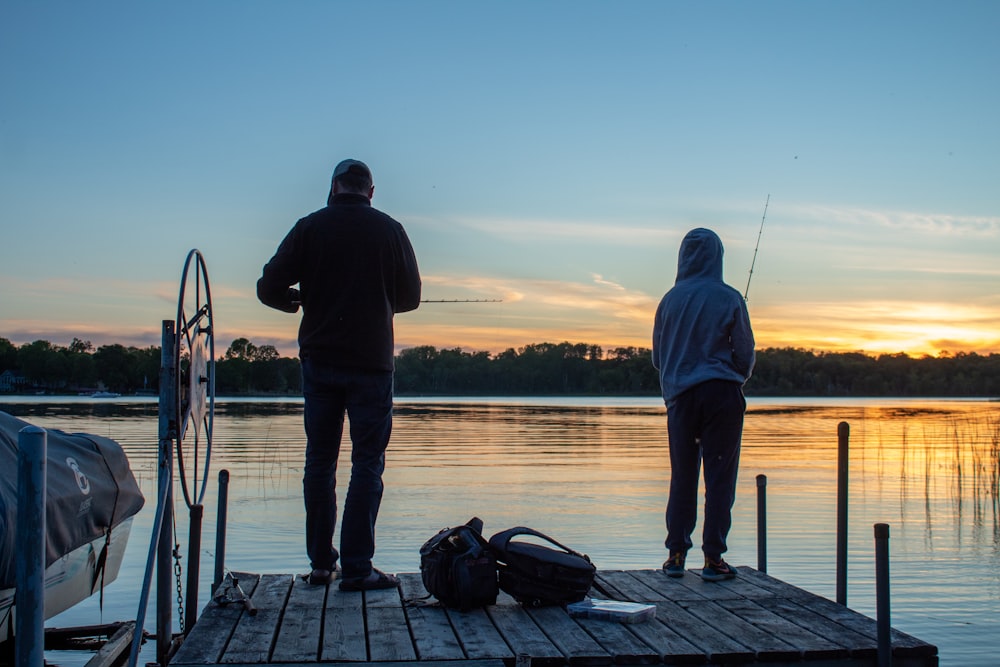 a couple of men standing on top of a pier