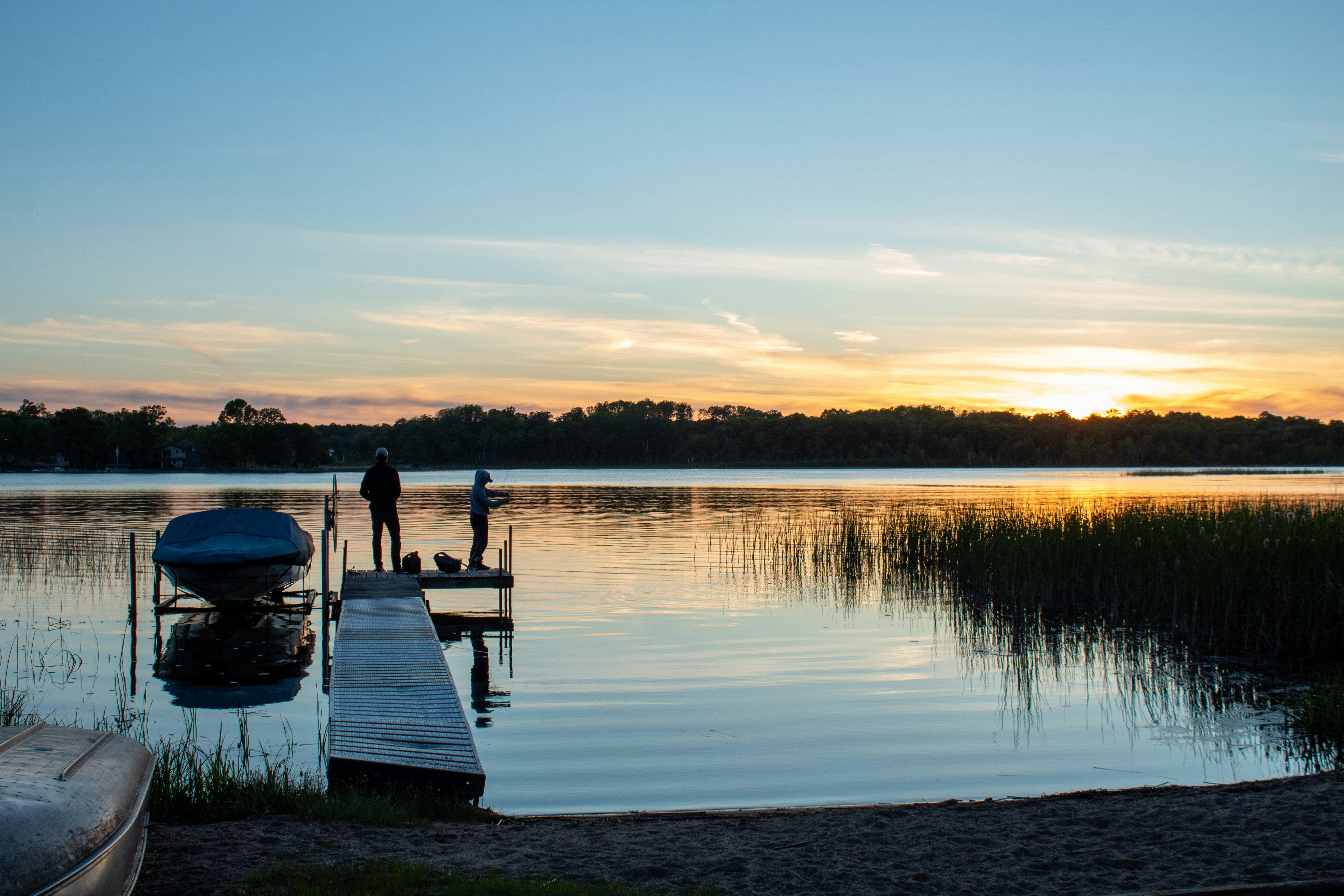 A couple of people standing on a dock next to a body of water photo