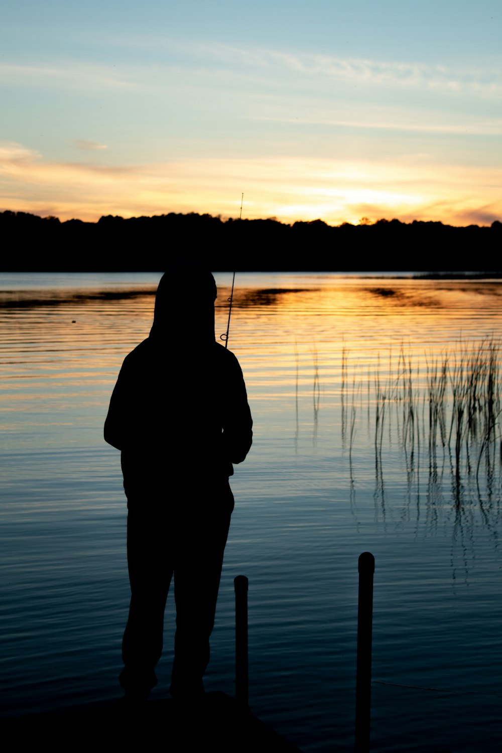une personne debout sur un quai avec une canne à pêche
