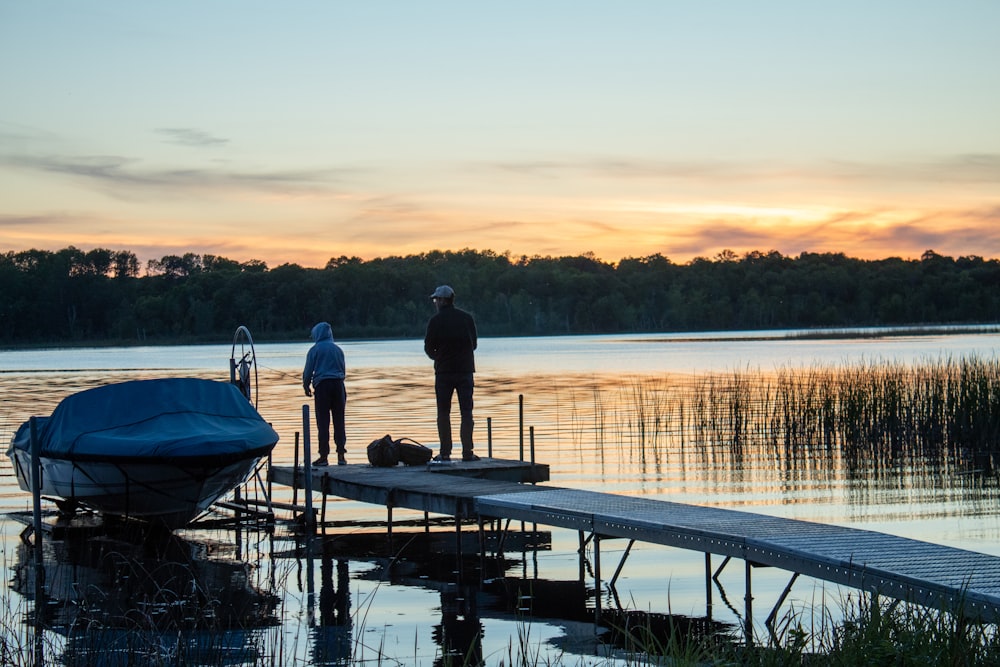 a couple of men standing on a dock next to a boat