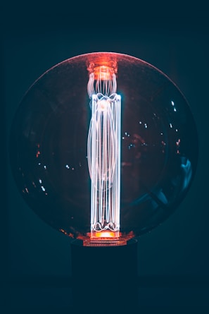 Modern LED bulb with a glowing hover effect illuminating a dark room with cool blue tones.