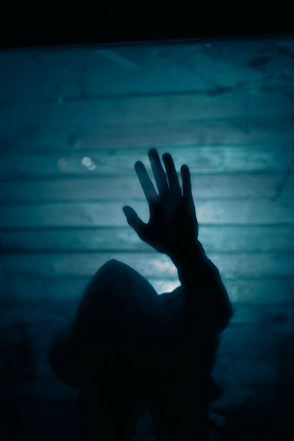 a silhouette of a hand reaching up into the air
