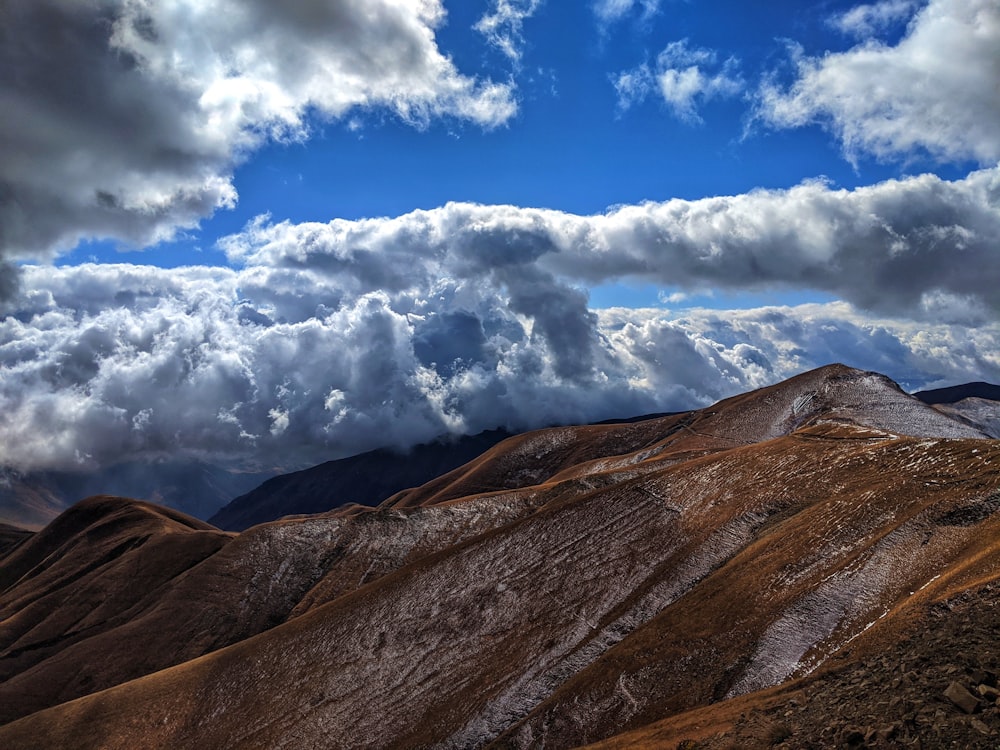 Braune und graue Berge unter weißen Wolken und blauem Himmel tagsüber