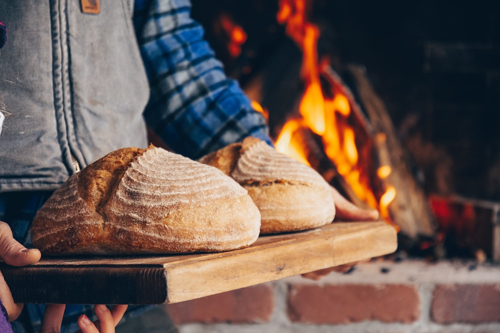 person in blue and white plaid long sleeve shirt holding bread