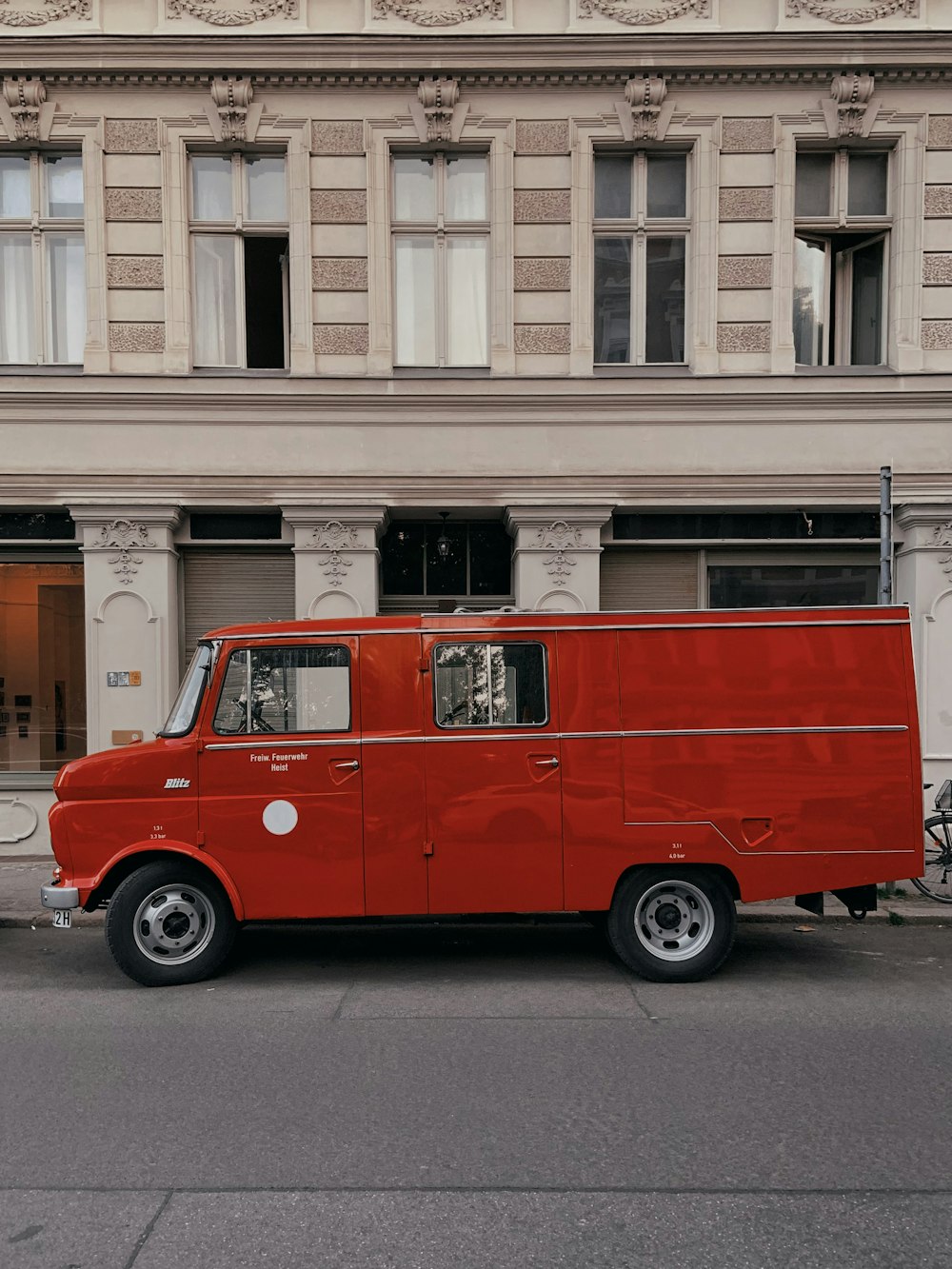 uma van vermelha estacionada em frente a um prédio