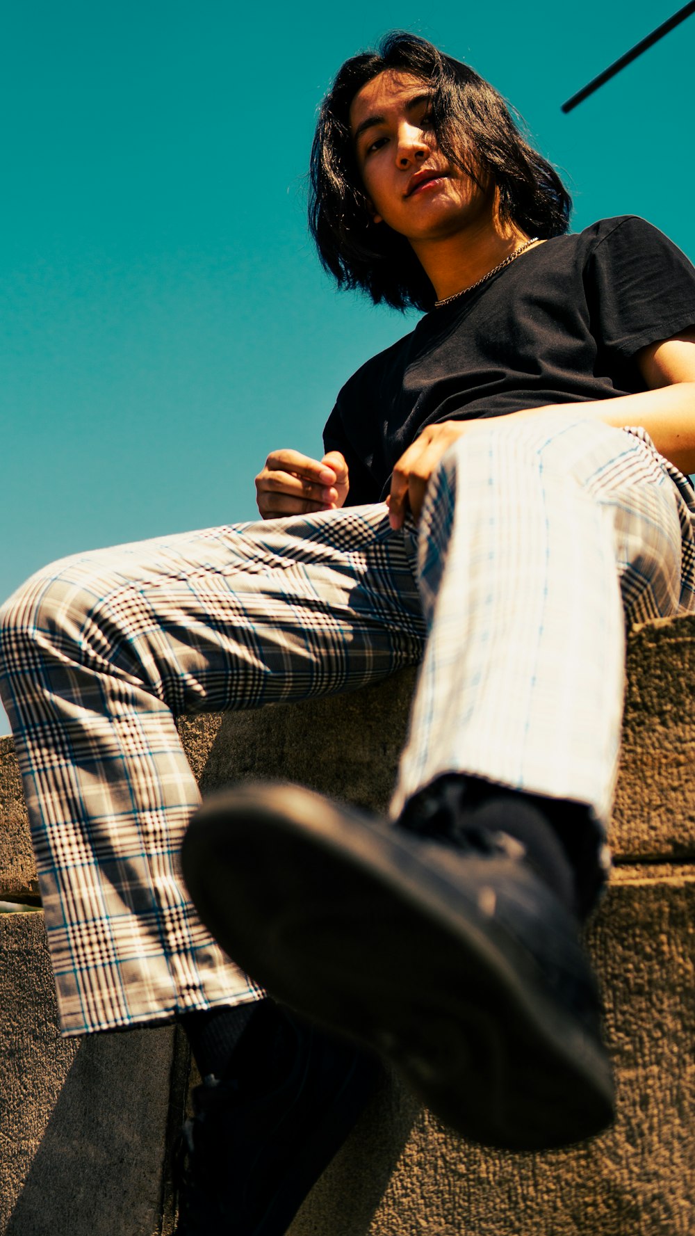 man in black t-shirt and white pants sitting on brown field during daytime