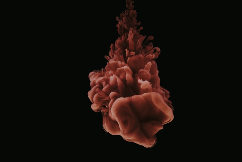 a red substance floating in the air on a black background