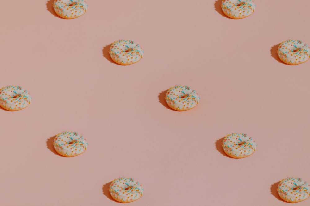 a pattern of donuts with sprinkles on a pink background