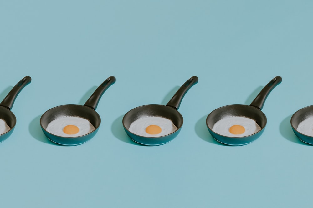 four frying pans with an egg in them
