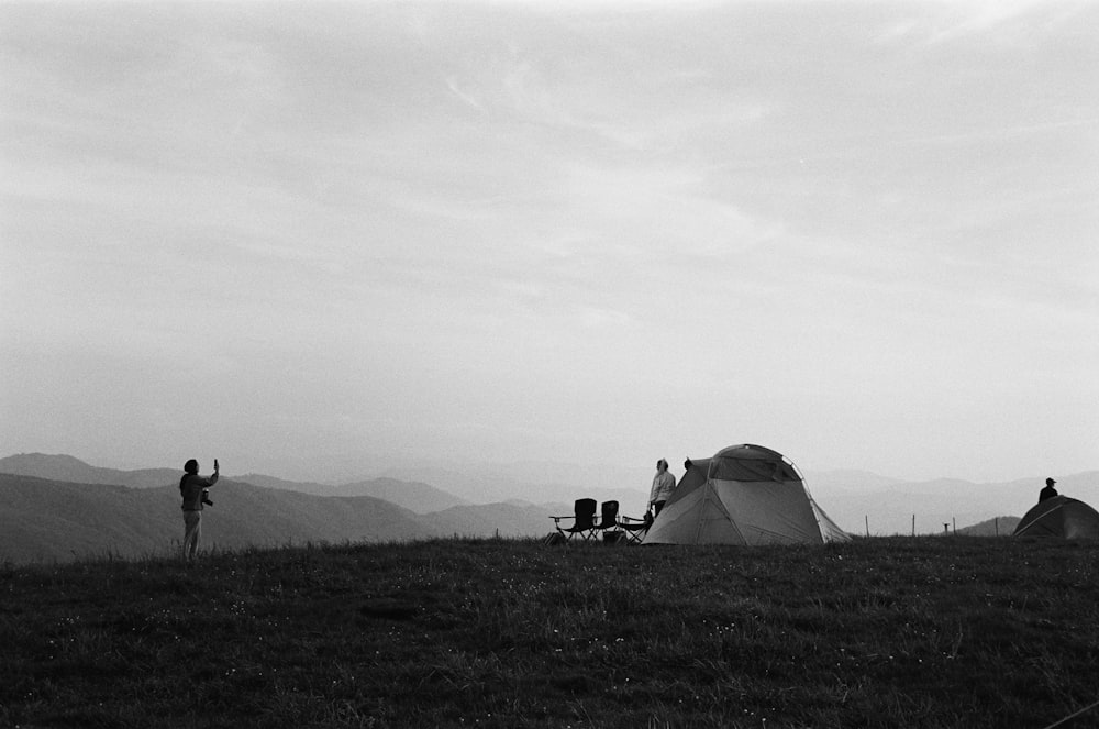 grayscale photo of people in tent on grass field