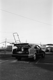 a black and white photo of a car with a surfboard on the back of