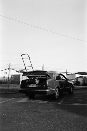 a black and white photo of a car with a surfboard on the back of