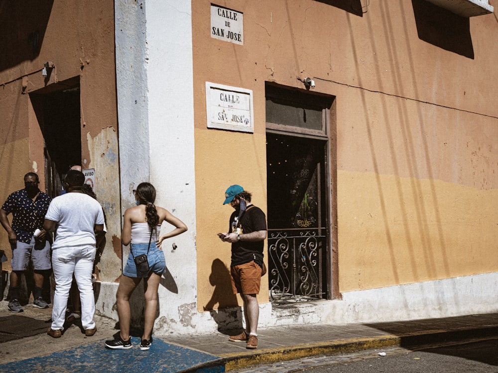 Uomo in maglietta bianca e jeans blu che cammina sul marciapiede durante il giorno