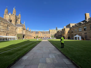 Historic UK university courtyard with students sitting on benches surrounded by classic stone architecture