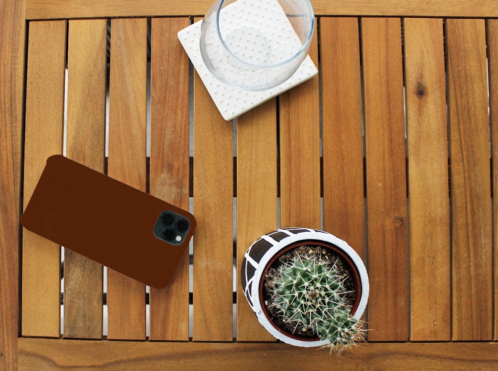 a wooden table topped with a phone and a cactus