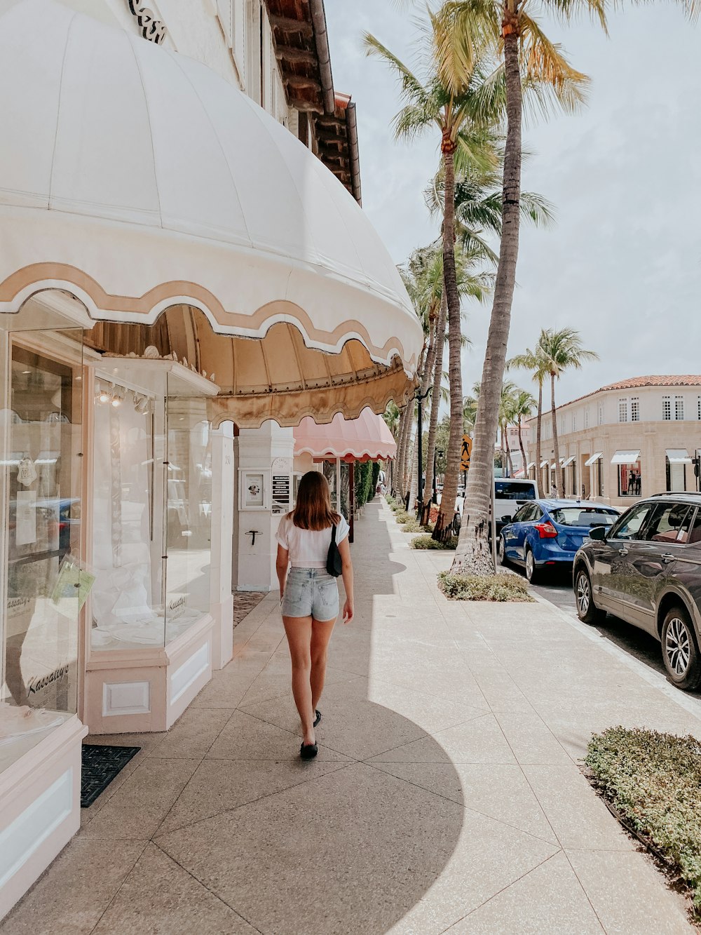 a woman walking down a sidewalk past a store