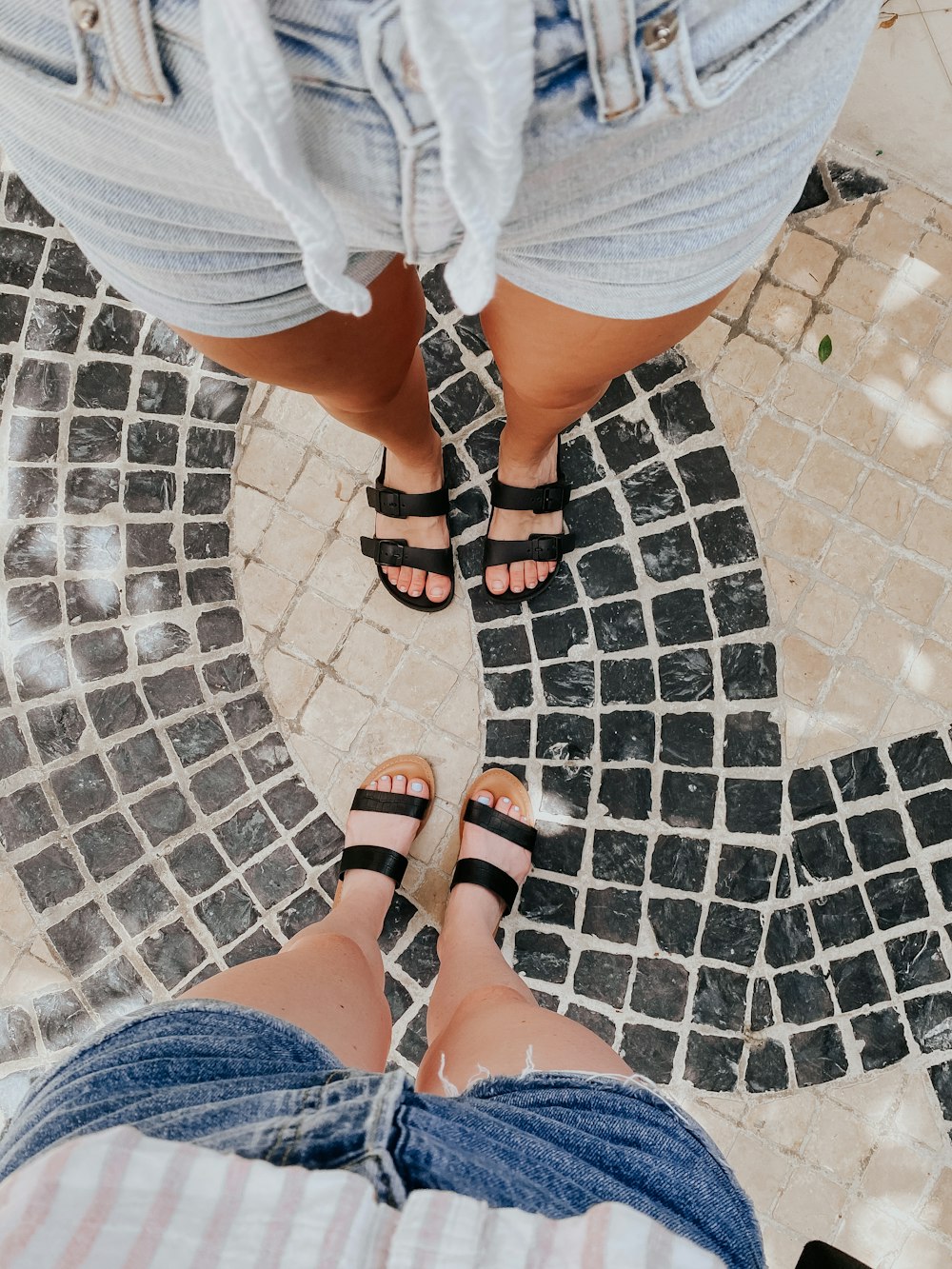 Person in blauen Jeansshorts und schwarzen Ledersandalen