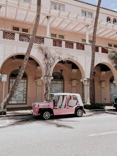 red and white car parked beside brown concrete building during daytime