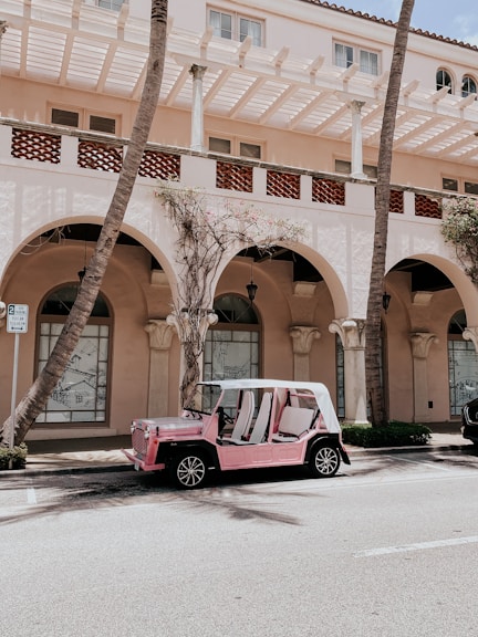 red and white car parked beside brown concrete building during daytime