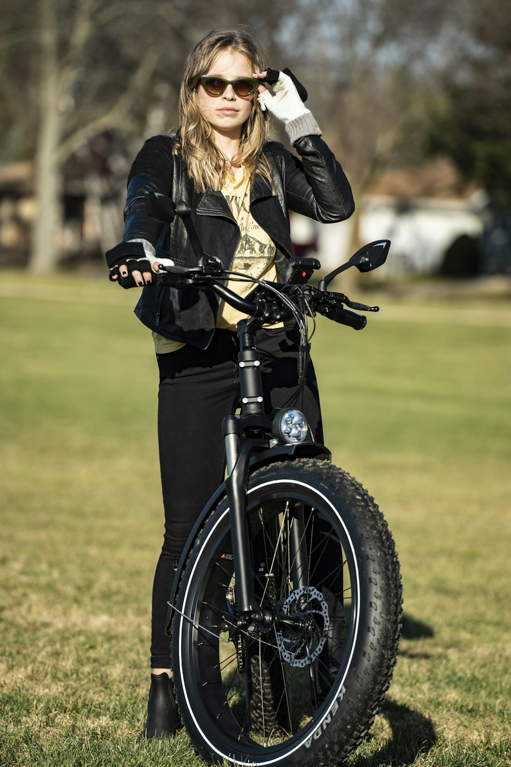 mulher na jaqueta de couro preta que monta a motocicleta preta durante o dia