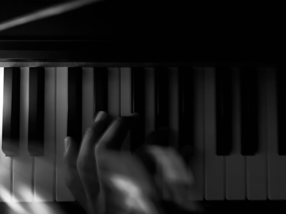 person playing piano in grayscale photography