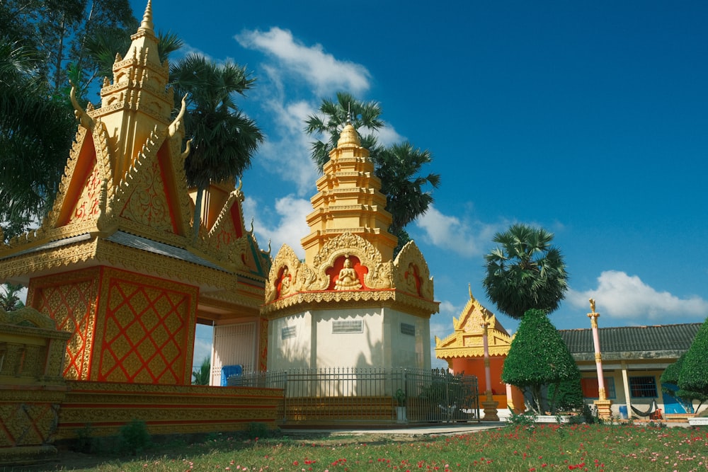 a group of gold and white buildings sitting on top of a lush green field