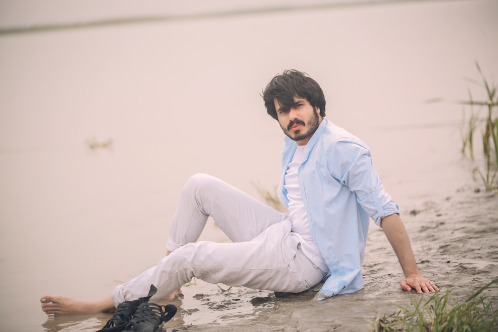 man in white dress shirt and gray pants sitting on gray concrete floor